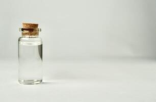 Transparent glass vial bottle container with brown cork stopper lid isolated on horizontal empty copy spaced white background. photo