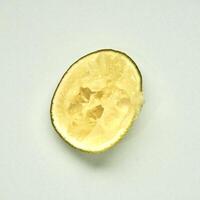 One piece of sliced in half lime citrus fruit after squeezed isolated on square white background from above angle view. photo