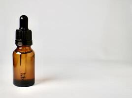One piece of brown transparent skin care bottle container with pipette cap isolated on horizontal empty copy spaced white background. photo