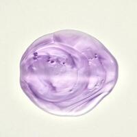Purple liquid body soap swatch texture isolated on square white background from above angle view. photo