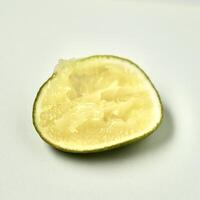 One piece of sliced in half lime citrus fruit after squeezed isolated on square white background. photo