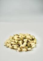 Pile of dried jasmine flower buds for aromatheraphy and tea ingredients isolated on vertical copy spaced plain background. photo