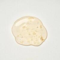 Yellow orange transparent liquid soap body care drop texture isolated on square white background from above angle view. photo