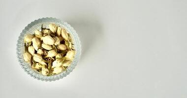 Dried jasmine flower buds for aromatheraphy and tea ingredients in round glass bowl isolated on horizontal copy spaced plain background from above angle view. photo