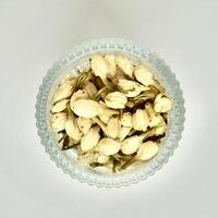 Dried jasmine flower buds for aromatheraphy and tea ingredients in round glass bowl isolated on square plain background from above angle view. photo