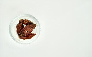 Dried gardenia organic food and tea ingredients in round glass bowl isolated on horizontal copy spaced white background from above angle view. photo