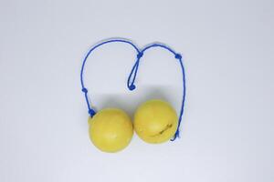 Two yellow fruits are tied to a blue string photo