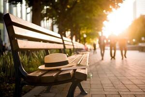 A bench holds a hat and book, lit by soft sunset along a tree lined path photo