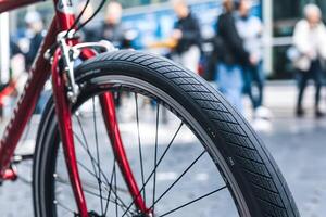Bicycle tire close up, red frame and blurred urban background emphasize dynamic scene photo