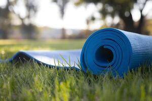 A yoga mat lies on lush grass under sunlight filtering through trees photo