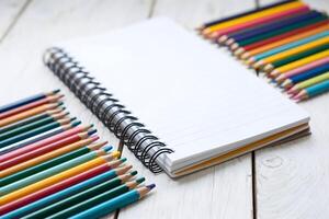 Spiral notebook surrounded by colorful pencils in an artistic, creative environment photo