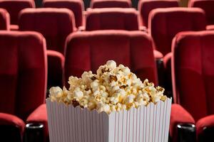 Cinema with red plush seats, popcorn container creating cozy, anticipatory atmosphere photo