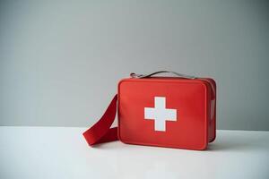 Red first aid kit with white cross, ready for emergency situations on white surface photo