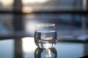 Glass of water on reflective surface, sunlight creating peaceful and serene glow photo