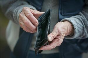 Older hands holding textured empty wallet, highlighting wrinkles and aged veins photo
