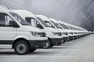 White vans parked in line, first van slightly blurred emphasizing depth and scale photo
