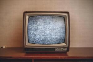 Retro CRT television on wooden surface displays static, evoking nostalgic simplicity photo