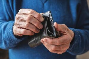 Older mans hands holding empty wallet, suggesting reflection and financial hardships photo