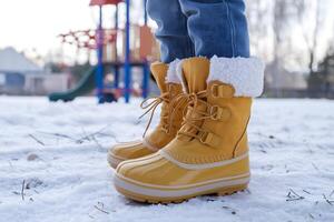 Yellow boots on snow, playground in background suggests crisp winter morning atmosphere photo