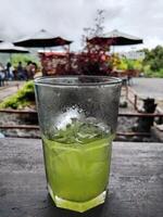 Half a glass of kiwi juice on the table outside the cafe photo