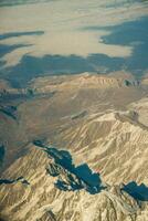 Aerial photo of the landscape with clouds, snowy mountains and view stretching all the way to the horizon