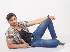 A man in jeans and a plaid shirt sitting on the floor photo