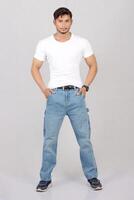 A man in jeans standing in front of a white background photo