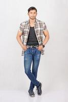 A man in jeans and a plaid shirt standing photo