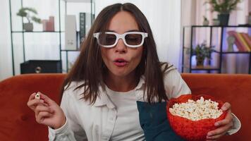 Woman sitting on couch eating popcorn and watching interesting TV serial, sport game online at home video