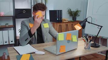 Tired sad exhausted businessman working on laptop at office with many sticker tasks, panic attack video