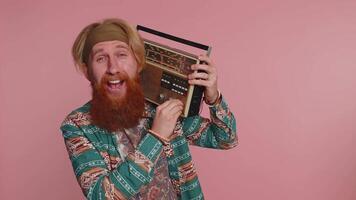 Hippie redhead man using retro vintage tape record player to listen music, disco dancing having fun video
