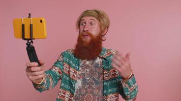 Impressed man blogger taking selfie on smartphone selfie stick, communicating call online video