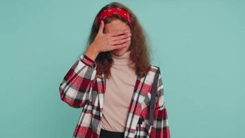 Young child girl kid closing eyes with hand showing stop gesture, confused shy scared to watch video
