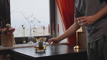 Man puts a kettle of tea and a cup on the table video