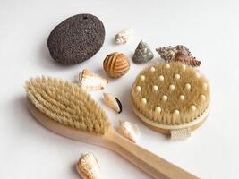 Coastal spa essentials. Natural brushes, pumice stone, and seashells on white background photo