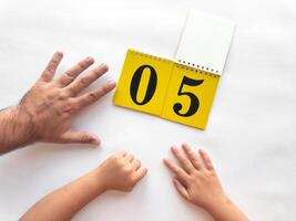 Adult and child hands counting with calendar showing number five on white background photo