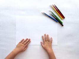 Child's hands ready to draw with colorful markers on white paper background photo