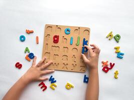Childs hands solving colorful alphabet puzzle for learning and play photo
