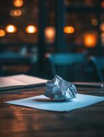 Crumpled paper symbolizing burnout on desk in dimly lit room photo