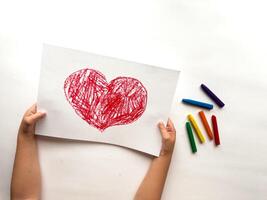 Childs colorful heart drawing with crayons on white background photo