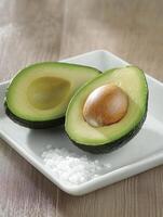 Fresh avocado halves with sea salt on a white plate photo