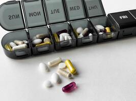 Organized weekly pill box with assorted medications and supplements photo