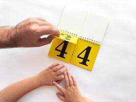 Hands changing date on yellow calendar pages, concept of time and planning photo