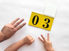 Counting hands with yellow calendar displaying number three for learning photo