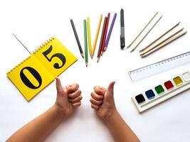 Creative art workspace with colorful pencils, paints, and calendar displayed on white surface photo