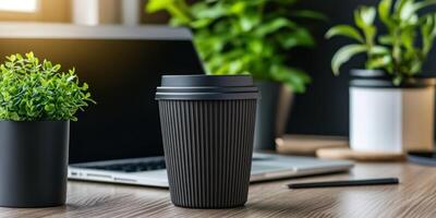 Reusable travel coffee cup on minimalist workspace with laptop and greenery photo