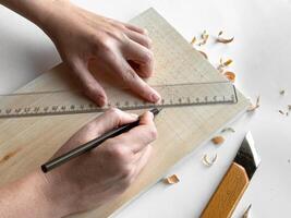 Hands drawing geometric patterns on wood with pencil and ruler photo