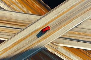 A bold red car crossing intersecting highways, showcasing dynamic lines and modern movement photo