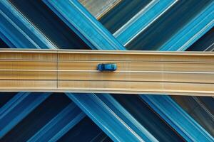 A sleek car glides over an intricate highway network captured from above, showcasing design and motion photo