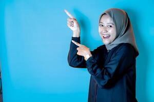 Asian woman wearing a hijab pointing in a certain direction photo
